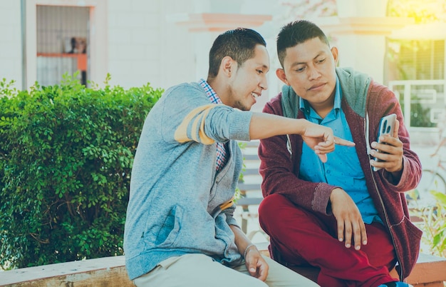 Hombre mostrando su celular a otro chico dos chicos revisando sus celulares Dos jóvenes comparando sus celulares