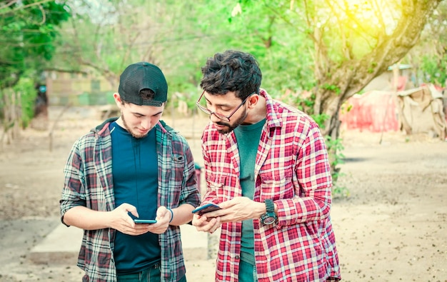 Hombre mostrando su celular a otro chico dos chicos revisando sus celulares Dos jóvenes comparando sus celulares