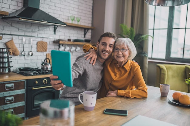 Hombre mostrando a su mamá cómo usar la tableta