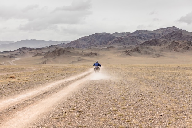 Hombre en moto en las estepas de Mongolia, en las colinas de Mongolia