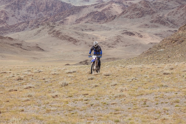 Hombre en moto en las estepas de Mongolia, en las colinas de Mongolia