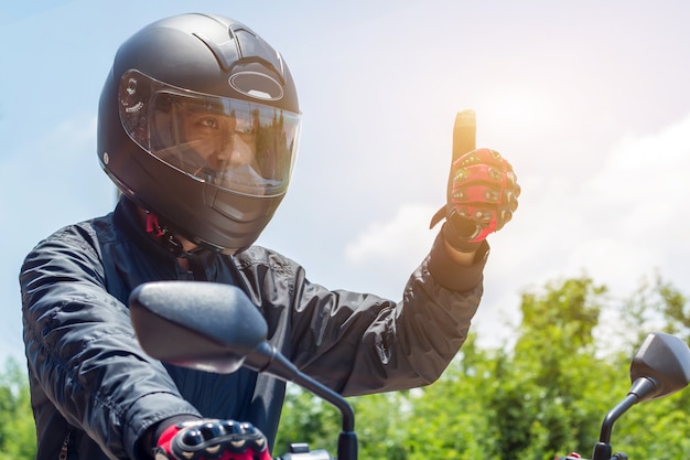 Hombre en una motocicleta con casco y guantes para motociclismo control del acelerador con luz solar