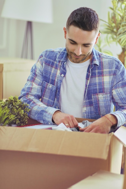 Un hombre en movimiento sentado en el suelo en un apartamento vacío Entre las cajas Comprobación de la lista de cosas