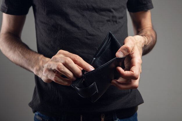 El hombre muestra una billetera de cuero vacía.