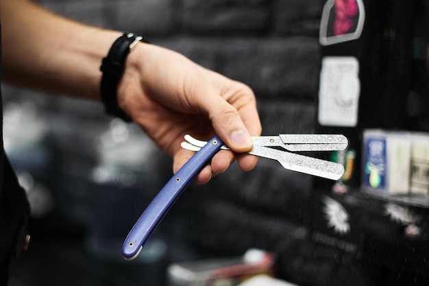 Hombre muestra multiherramienta con tijeras y maquinilla de afeitar en barbería