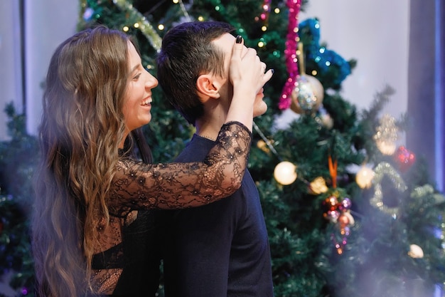 Un hombre y una mujer se abrazan y se felicitan cerca de un árbol de Navidad decorado.