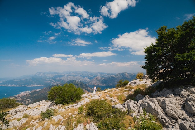 Un hombre y una mujer se abrazan en el monte Lovcen, una vista panorámica de la bahía de Kotor se abre en