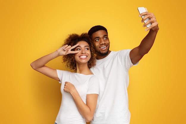 Un hombre y una mujer afroamericanos felices haciendo selfies.