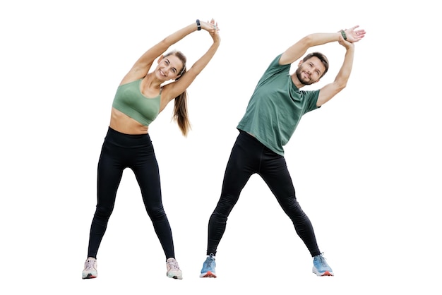 Hombre y mujer alegres con ropa de fitness haciendo flexiones laterales que promueven la flexibilidad contra un fondo blanco