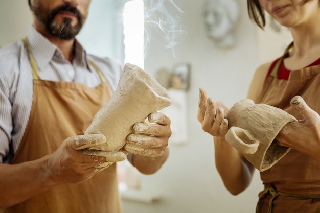 Hombre y mujer. Alfareros hábiles profesionales masculinos y femeninos haciendo tazas y vasos juntos