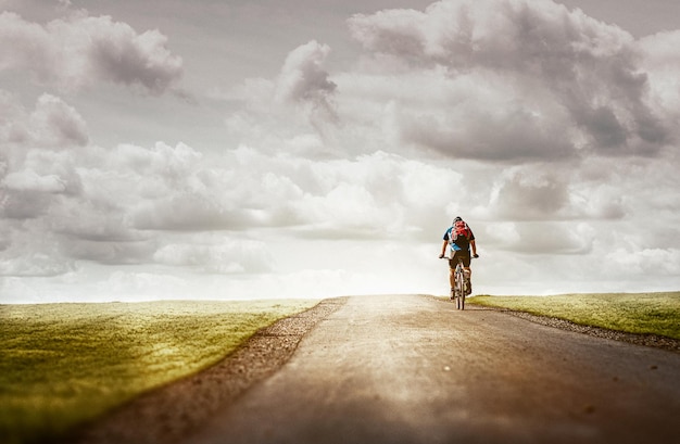 Un hombre y una mujer andan en bicicleta por una carretera con un cielo nublado de fondo.