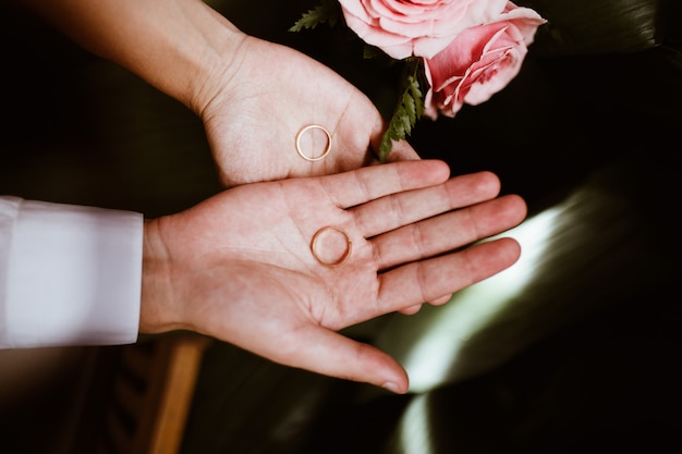 Hombre y mujer con anillos de boda en manos abiertas y ramo de novia. Intercambiar anillos. feliz novio y novia. Concepto del día de la boda