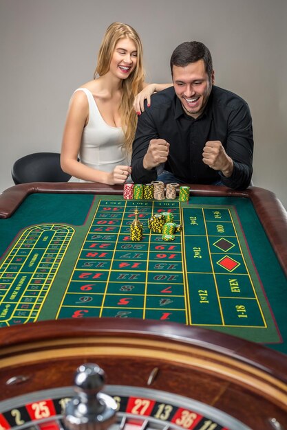 Hombre y mujer animando en la mesa de la ruleta en el casino