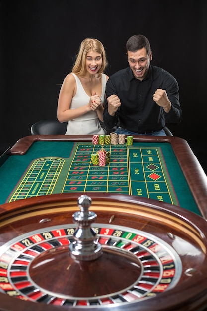 Hombre y mujer animando en la mesa de la ruleta en el casino