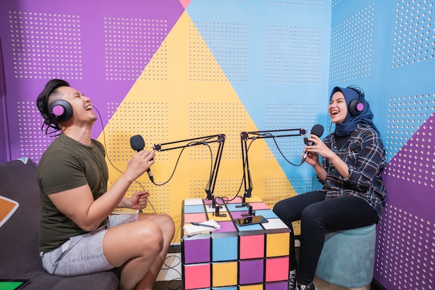 Hombre y mujer asiática musulmana hablando juntos en el estudio de podcast