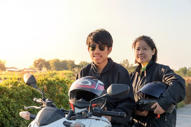 Hombre y mujer asiáticos con casco y usar y abrocharse antes de andar en bicicleta grande moto en la carretera por seguridad