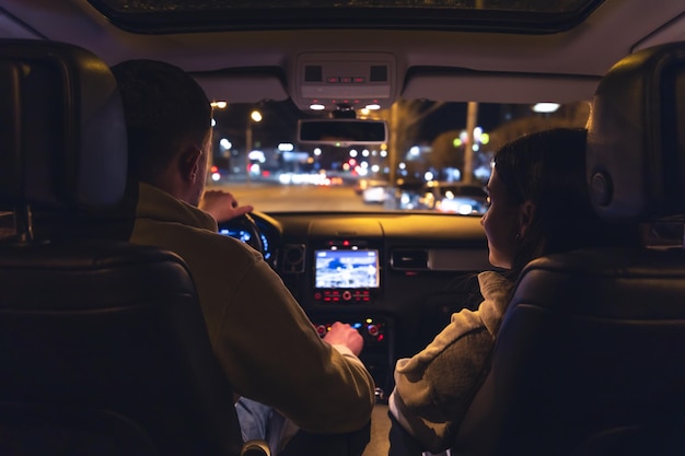 Hombre y mujer en un auto en vista nocturna desde el auto