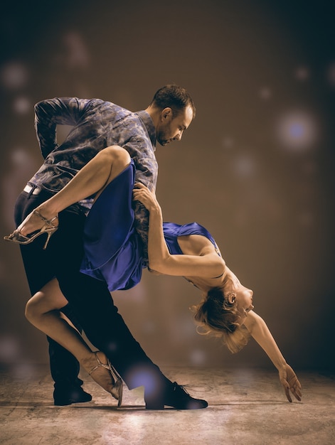 Foto un hombre y una mujer bailando tango argentino sobre fondo gris studio