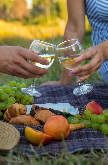 Un hombre y una mujer beben vino en un picnic. Enfoque selectivo. Naturaleza.