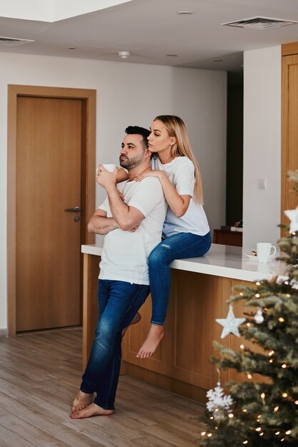 Hombre y mujer bebiendo café por la mañana en la cocina en la víspera de Navidad