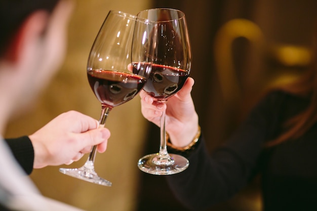 Hombre y mujer bebiendo vino tinto. En la imagen, manos de primer plano con gafas.