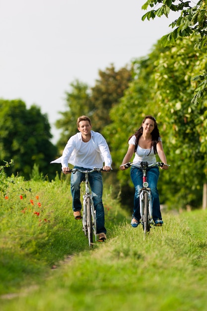 Hombre y mujer en bicicleta por un camino soleado