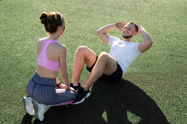 Hombre y mujer bombean sus abdominales en el parque sobre la hierba