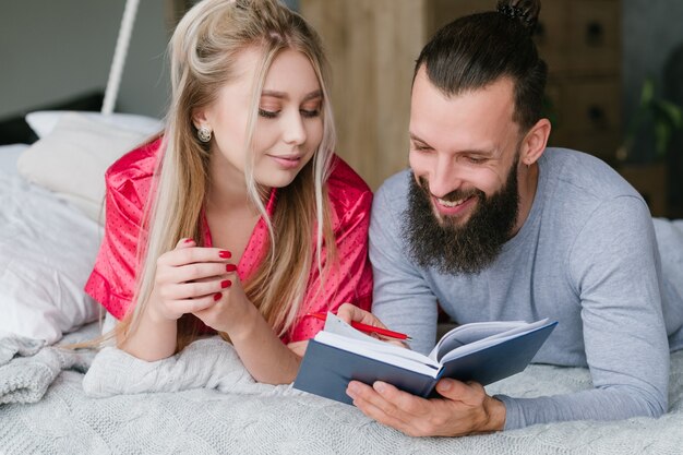 Hombre y mujer en la cama tomando notas.