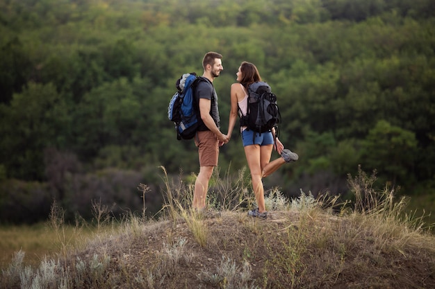 Un hombre y una mujer caminan por las montañas con mochilas.