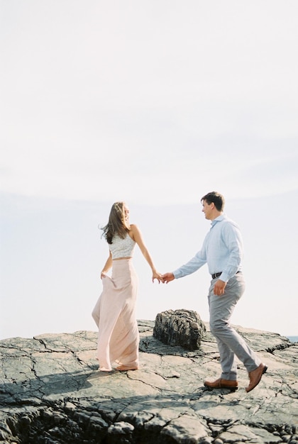 Hombre y mujer caminando de la mano en un acantilado