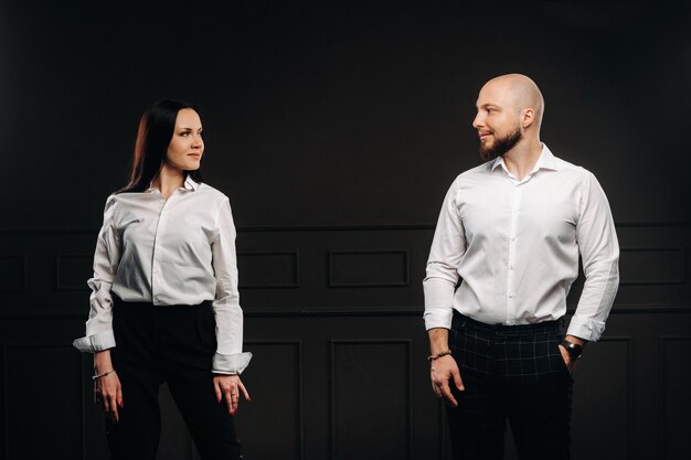 Un hombre y una mujer con camisas blancas sobre un fondo negro. Una pareja de enamorados en el interior del estudio.