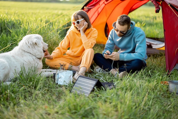 Hombre y mujer cargando teléfonos con panel solar mientras viaja