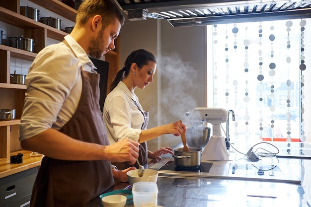 Hombre y mujer cocinando juntos en la cocina de la panadería. Productos de repostería de preparación profesional.