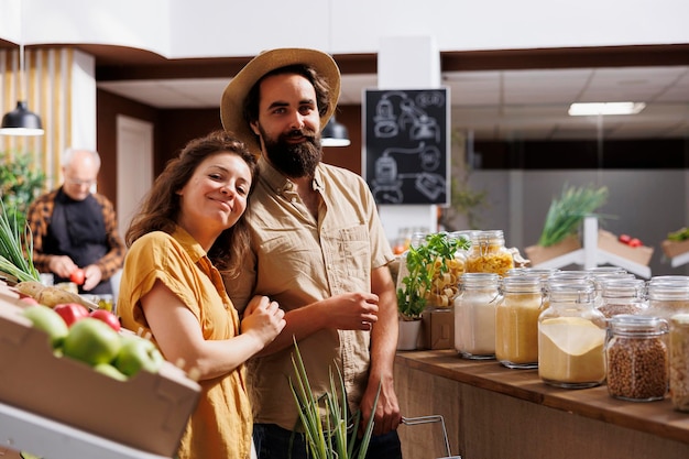 Hombre y mujer comprando en una tienda de residuos cero, buscando productos saludables a granel de origen local. Una pareja que vive conscientemente comprando productos básicos de despensa en una tienda local del vecindario