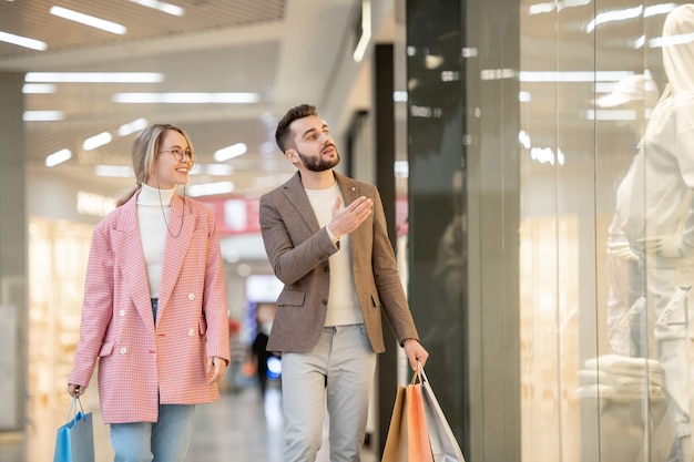 Un hombre y una mujer de compras en el centro comercial contemporáneo.