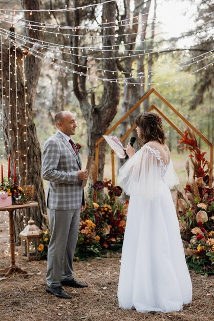 El hombre y la mujer se comprometieron en el bosque de otoño en la ceremonia de boda decorada