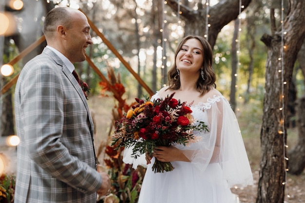 El hombre y la mujer se comprometieron en el bosque de otoño en la ceremonia de boda decorada