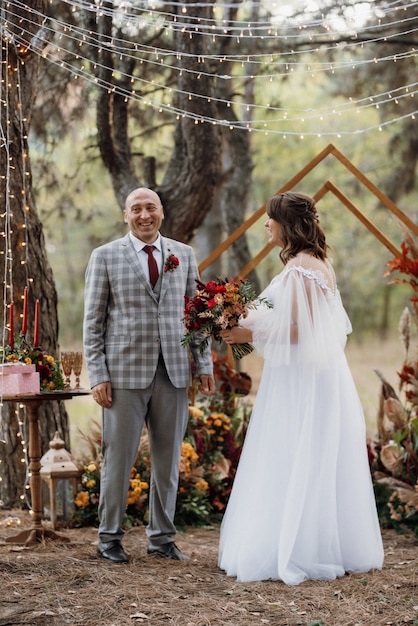 El hombre y la mujer se comprometieron en el bosque de otoño en la ceremonia de boda decorada