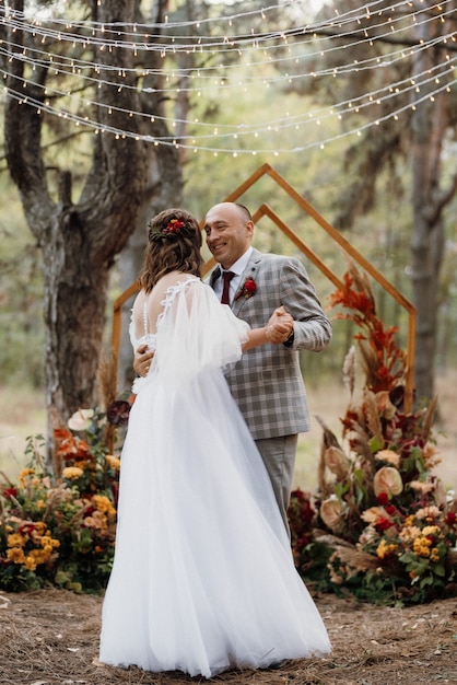 El hombre y la mujer se comprometieron en el bosque de otoño en la ceremonia de boda decorada