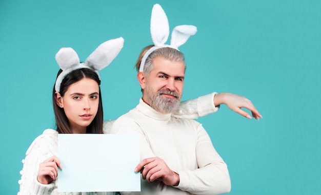 El hombre y la mujer del conejito de pascua sostienen el tablero para el banner de texto con el espacio de copia de la pareja de conejitos divertidos