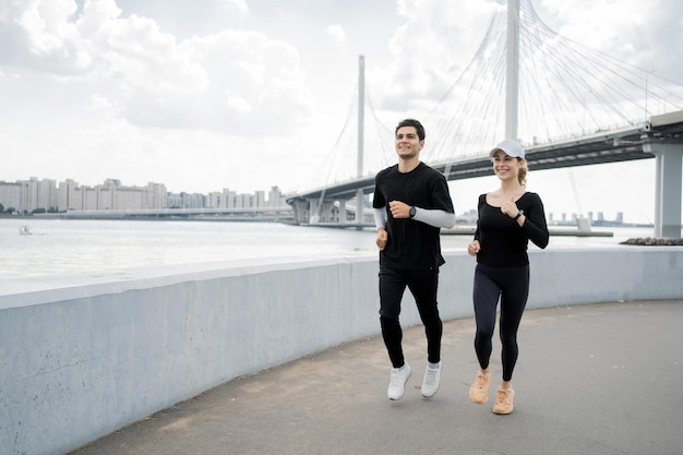 Un hombre y una mujer corredores haciendo ejercicio activo corriendo en la ciudad usando un brazalete de fitness