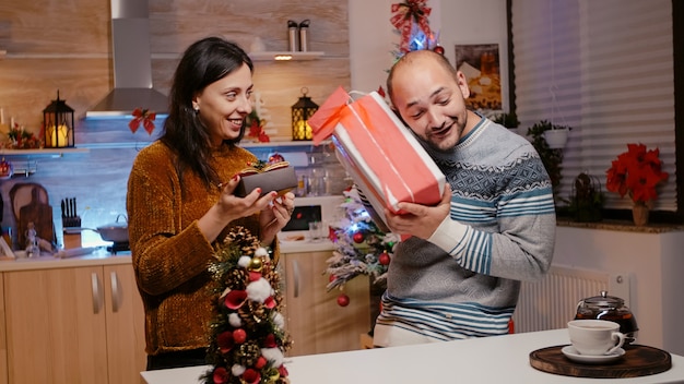 Hombre y mujer dando cajas de regalo el uno al otro para Navidad