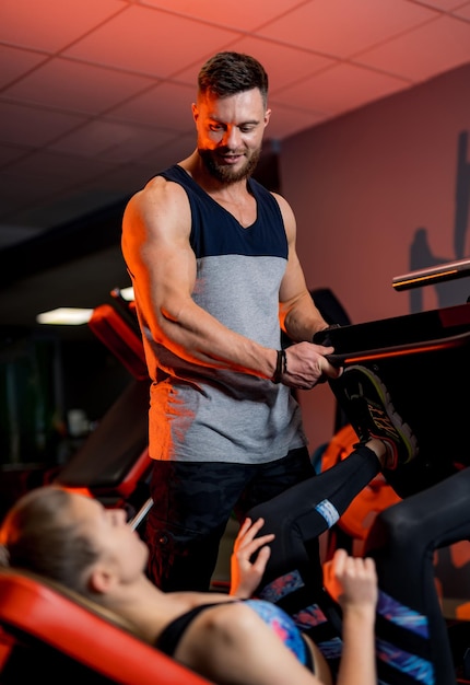 Hombre y mujer deportivos haciendo ejercicios en el gimnasio contemporáneo. Entrenador personal realiza curso deportivo. Estilo de vida activo.