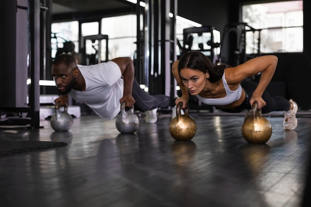 Hombre y mujer deportivos haciendo flexiones en un gimnasio