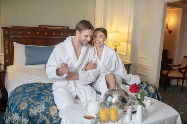 Un hombre y una mujer desayunando en el dormitorio.