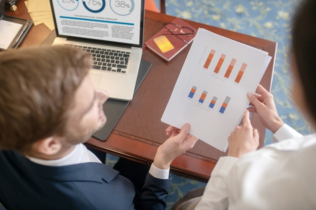 Un hombre y una mujer discutiendo diagramas en el informe.