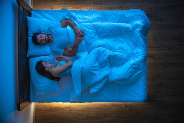 El hombre y una mujer durmiendo en la cama. vista desde arriba, tarde noche