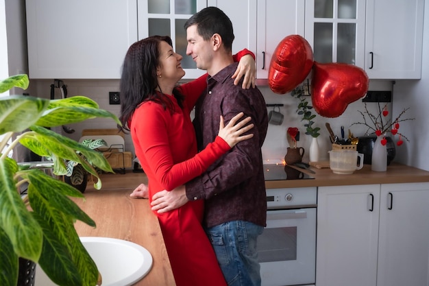 Hombre y mujer enamorados cita en casa en la cocina abrazos felices Día de San Valentín pareja feliz historia de amor Nido de amor vivienda para familia joven