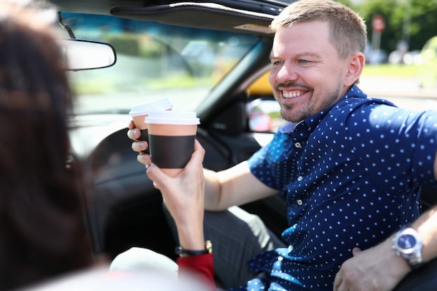 El hombre y la mujer están conduciendo en coche y tomando café