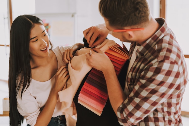 El hombre y la mujer están eligiendo el color para la ropa.